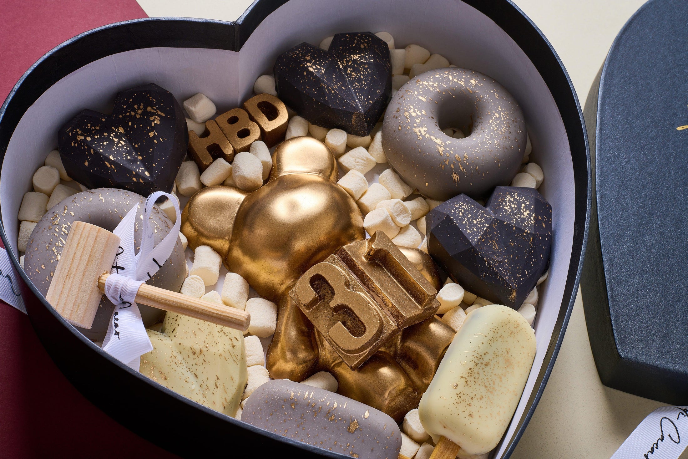 Chocolates para cumpleaños, caja en forma de corazón realizada con chocolate de leche y chocolate blanco. Vista de cerca.