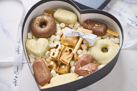 Chocolates para cumpleaños, caja en forma de corazón realizada con chocolate de leche y chocolate blanco. Vista de cerca.