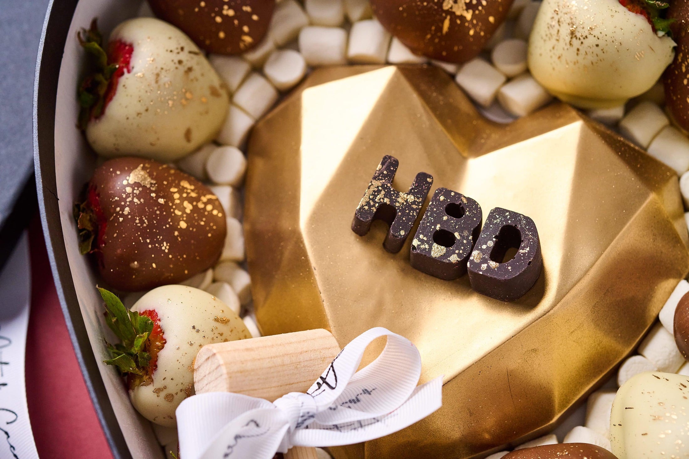 Chocolates para cumpleaños, caja en forma de corazón realizada con chocolate de leche, chocolate blanco y fresas cubiertas de chocolate. Vista de cerca.